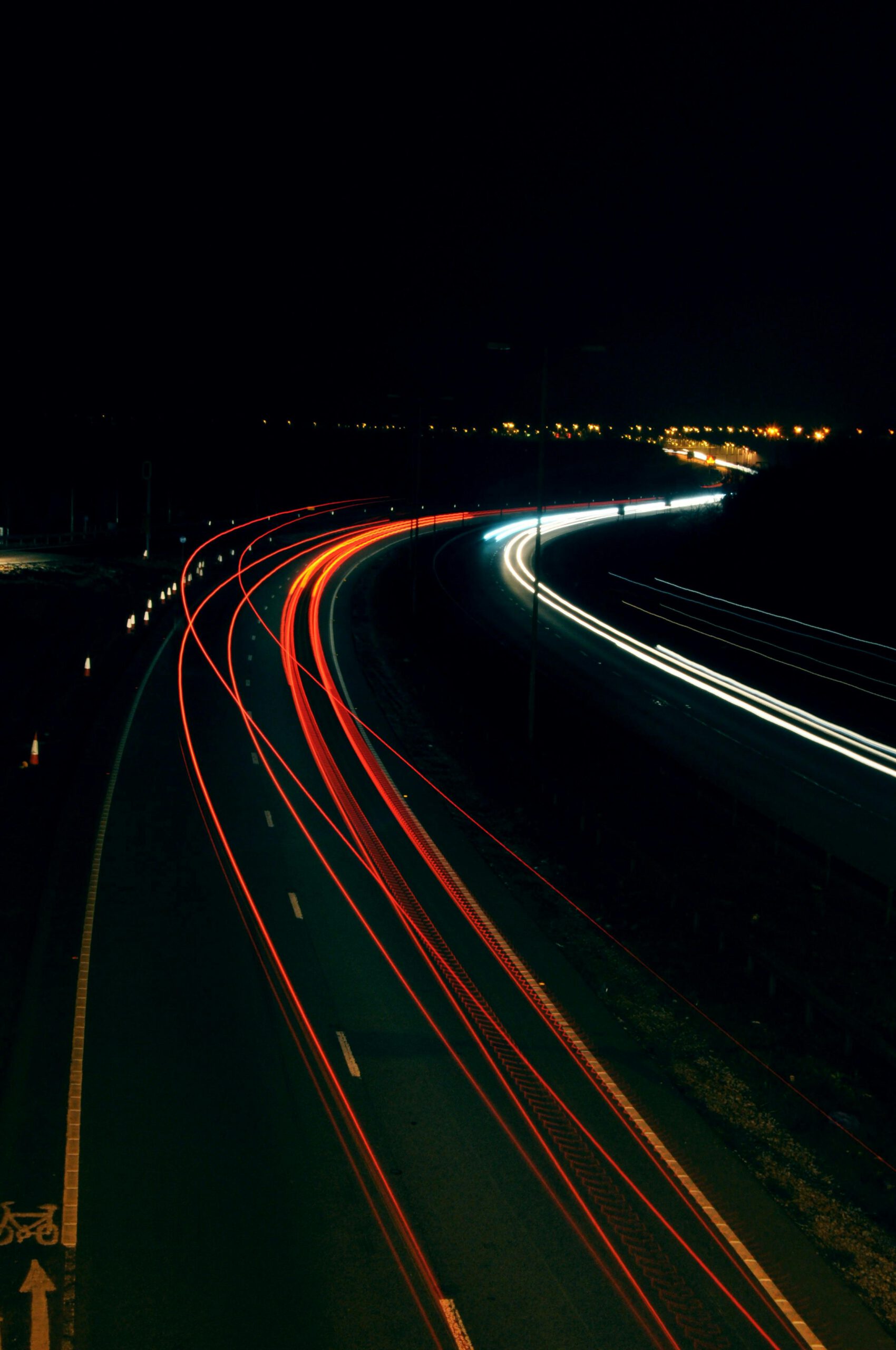 Long exposure photo capturing light trails on a highway at night, illustrating dynamic motion.